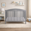 Gray crib in a nursery with toys and decor
