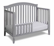 Gray crib with a white mattress on a white background