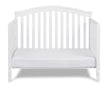 White crib with a white mattress on a white background