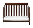 Wooden crib with white mattress on a white background