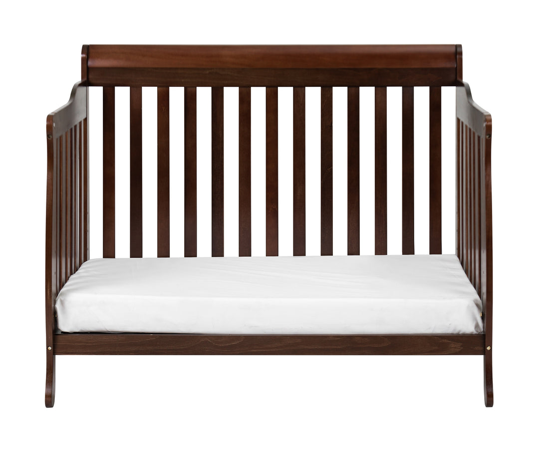 Wooden crib with white mattress on a white background