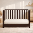 Wooden crib with white mattress in a nursery setting