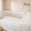 Nursery room with white crib and changing table against a beige wall.