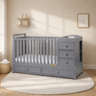 Gray crib with changing table in a nursery setting